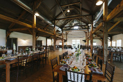 large room with post and beam vaulted ceiling and long rectangular wood tables.