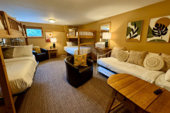 guest home lower level bunk room featuring two bunk beds, a day bed, a coffee table, small swivel couch, and small window.