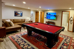 guest home featuring pool table, sofa, tv, and doors to bathroom and bunk room on ground floor.