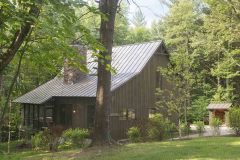 exterior of brown wooden house with steep metal roof in summer.