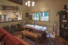 Dining area with long wood table and bench peeking over counter to kitchen.