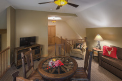 living area with round 'wagon wheel' table tv  and couch. celing fan with light.