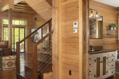 Wooden Interior of Foley Farmhouse, showing powder room to the right with water running, stairs in center, and back sliding doors to back patio.