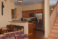 Mountain Top Resort Grand Vista Guest House staircase and kitchen view with wood cabinets and stainless refrigerator.
