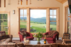 Mountain Top Resort Grand Vista Guest House living room with fabric arm chairs and large windows showing view out to green meadow and hills.