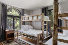 bunk room with two bunk beds with full beds on bottom with arched windows. 