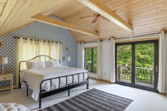 room off of the master bedroom with a large bed, tall ceilings, and mini deck. 