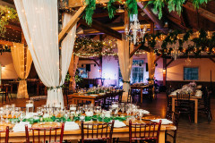 Mountain Top Resort reception hall with wooden beams and farmhouse tables  with wooden chairs. drapery and greens hanging from rafters.