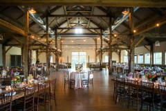Mountain Top Resort reception area in barn with exposed wooden beams, wooden floors and a mixture of wooden rectangular tables and round tables with white linens.