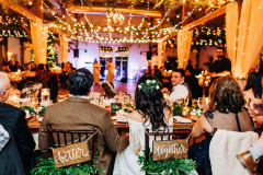 Mountain Top Resort reception hall with wooden beams and farmhouse tables  with wedding guests sitting in them.  lights and drapery hanging from beams.