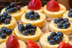 mini cheese cakes with strawberries and blueberries on top.