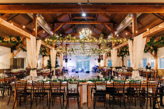Mountain Top Resort reception hall with wooden beams and farmhouse tables .  lights and drapery hanging from beams.