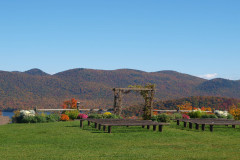 view from garden to wooden building against mountains covered in autumn foliage. Blue sky.