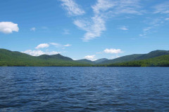 view from 'on' lake of water and surrounding mountains. Abundant blue sky.