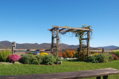 arbor with garden on either side and blue sky and mountains visible in background.