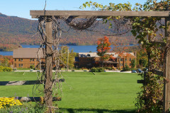 arbor with garden on either side and building, blue sky and mountains visible in background.