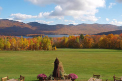 view from patio to  mountains covered in autumn foliage. Blue sky.
