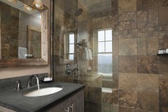 Bathroom with slate tiled wall shower and glass doors, soapstone sink and mirror.