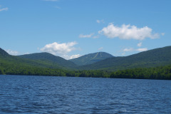 view from 'on' lake of water and surrounding mountains. Abundant blue sky.