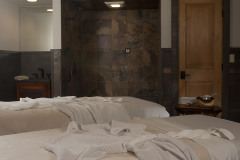 2 spa massage service beds with white linens and robes draped on them.