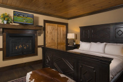 Bedroom with sleigh bed, wall fireplace, wooden closet doors and tv.