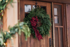 Wreath with red scarf hanging on wooden door in front of plant at Mountain Top Inn & Resort in Chittenden, VT