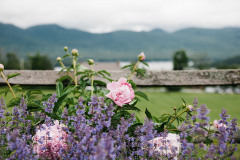 Group of pink and purple flowers in front of wooden fence with lake and mountains in background at Mountain Top Inn & Resort in Chittenden, VT