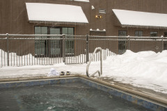 Mountain Top Resort in-ground hot tub outside brown barn building in winter.