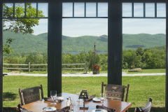 view out floor to ceiling windows from dining table to summer mountain view