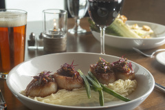Mountain Top Resort Restaurant Seared Scallops with mashed potatoes & green beans on white plates next to glass of beer and glass of red wine