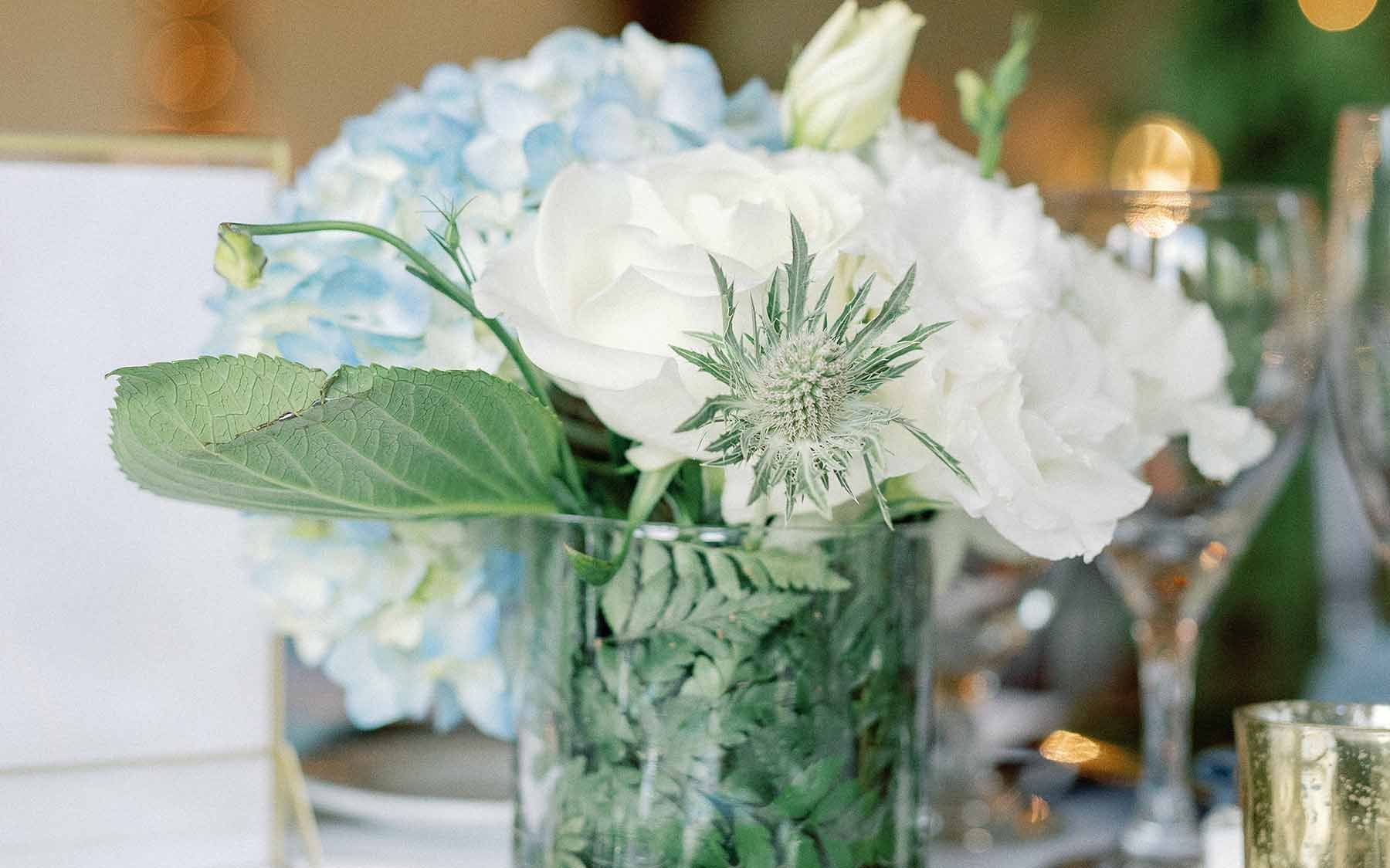 Blue and white flowers in a glass vase on a table.
