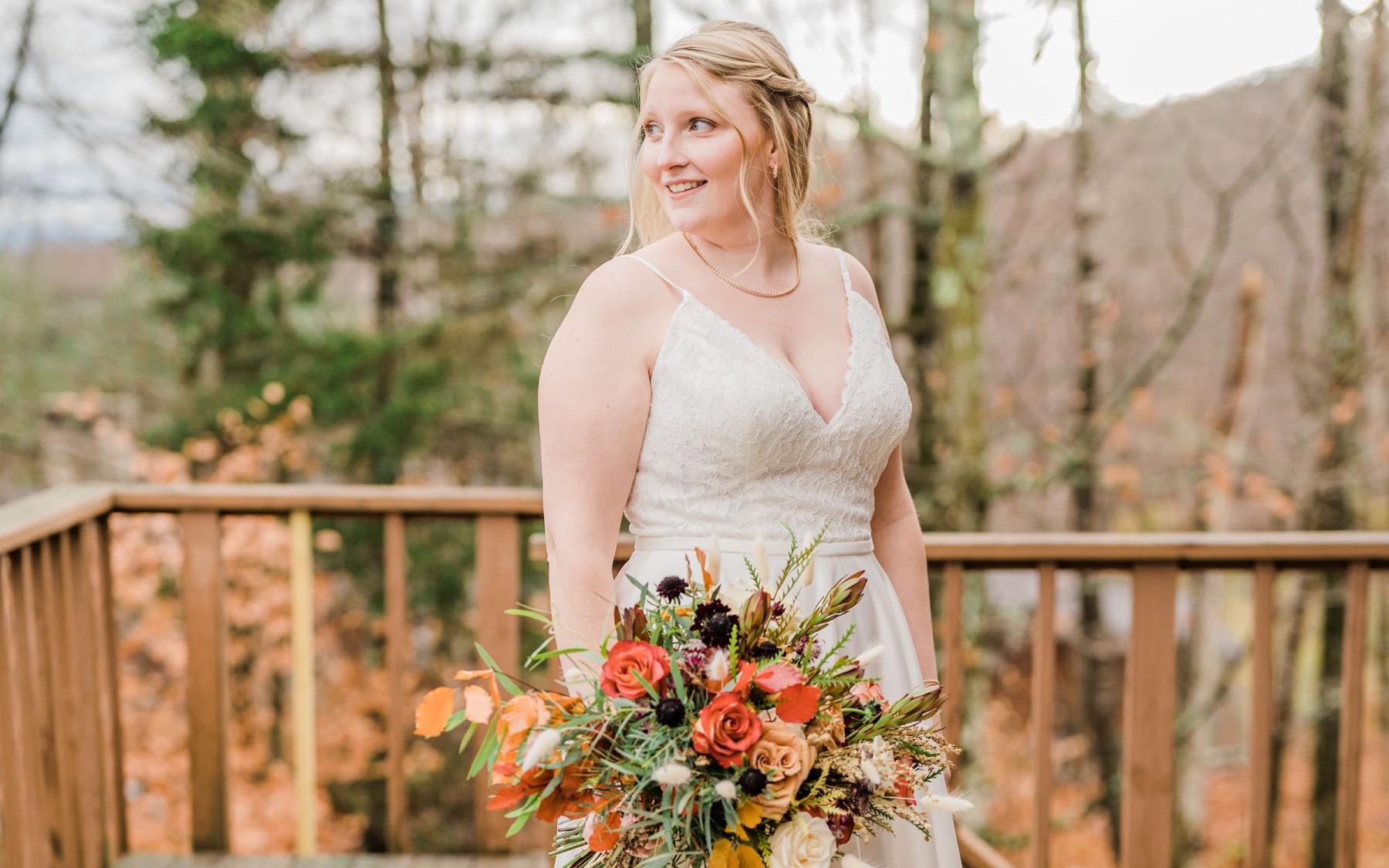 photo of bride holding fall themed bouquet on deck of guest house