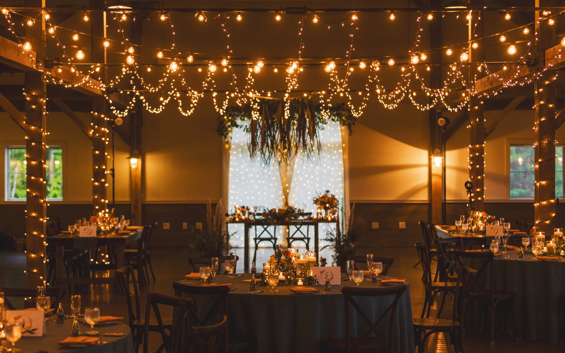 event barn with lights and hanging ladder with the sweetheart table focused in the background.
