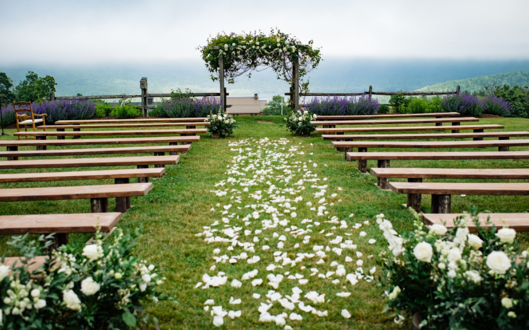 wedding knoll with decor and petals in aisle on foggy day.