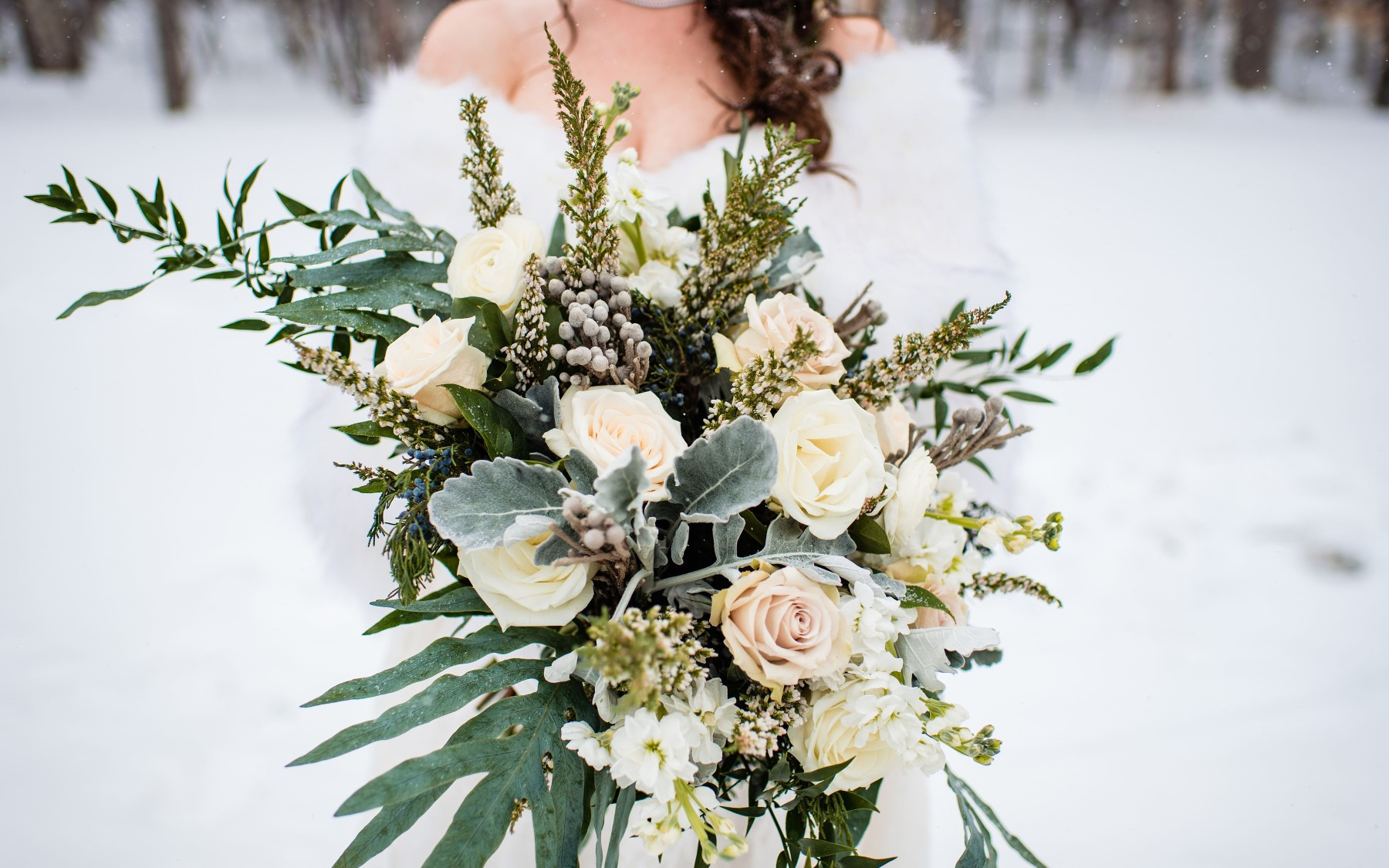 floral bouquet featuring white roses, greenery, and other floral.
