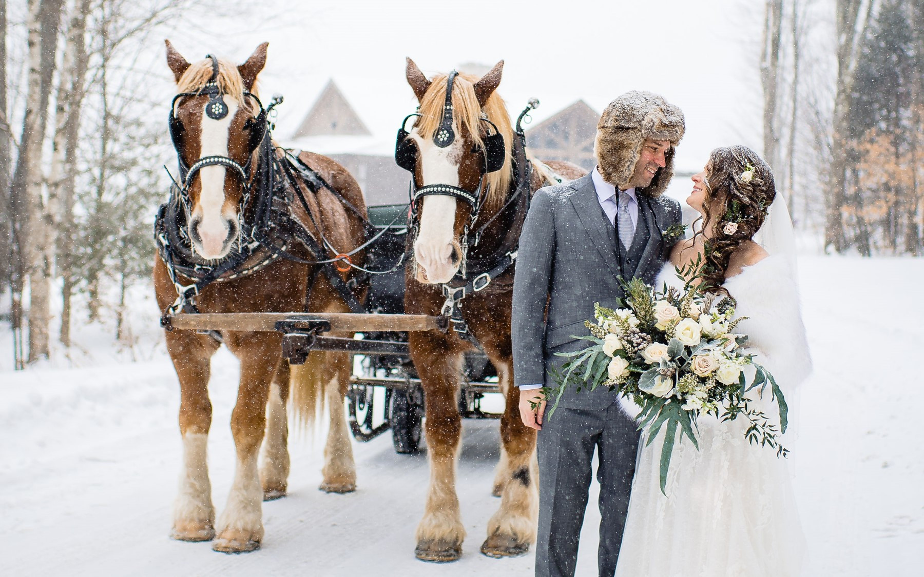 bride and groom in front of horse drawn sleigh in winter.
