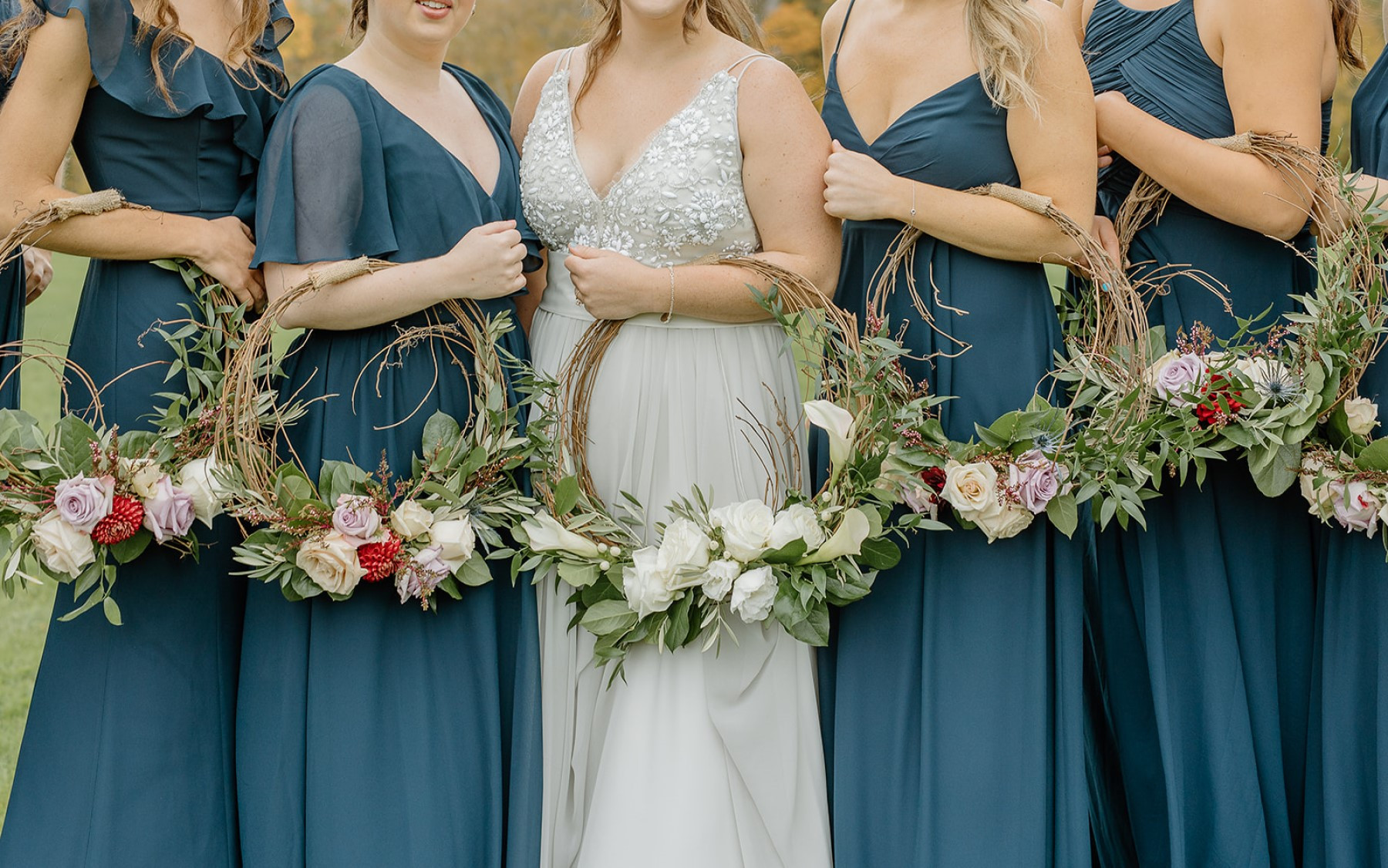 floral bouquet rounds being held by bride and four bridesmaids in blue dresses