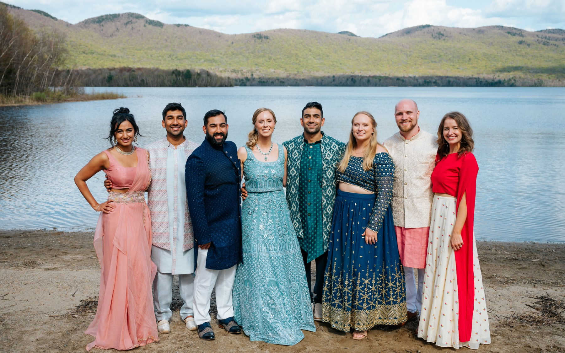 photo of bride and groom with family members in front of lake in indian style garments