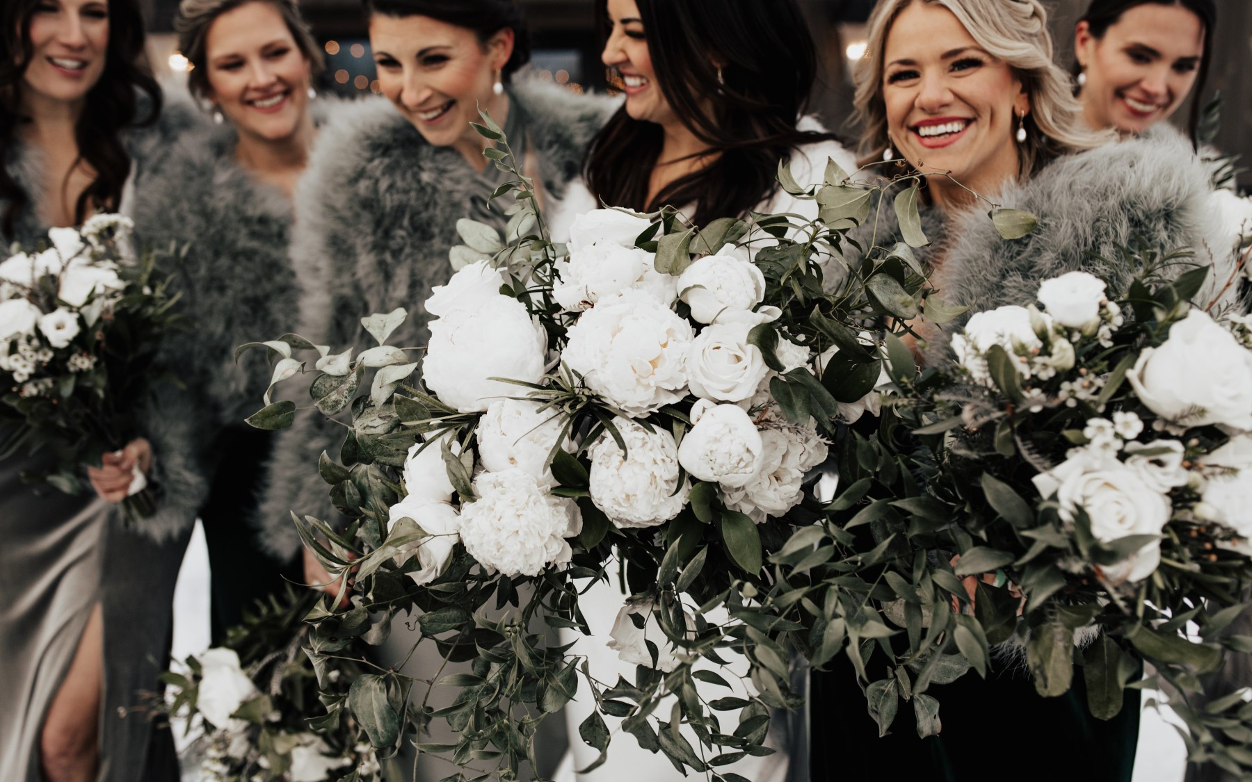 close up of floral arrangements for winter wedding featuring women in background smiling.
