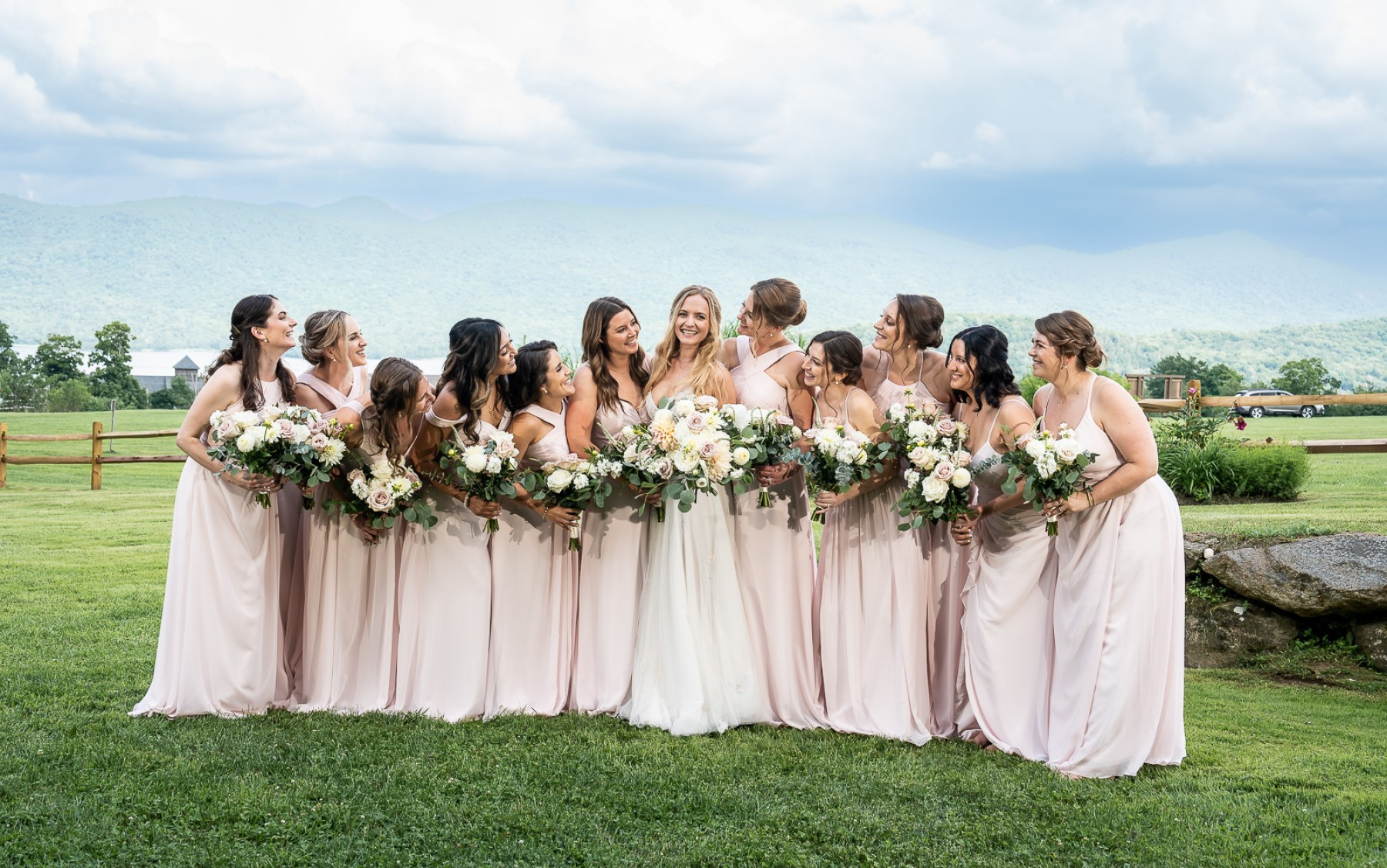 bride standing in middle with eleven bridesmaids in pink dresses all holding wedding bouquets.