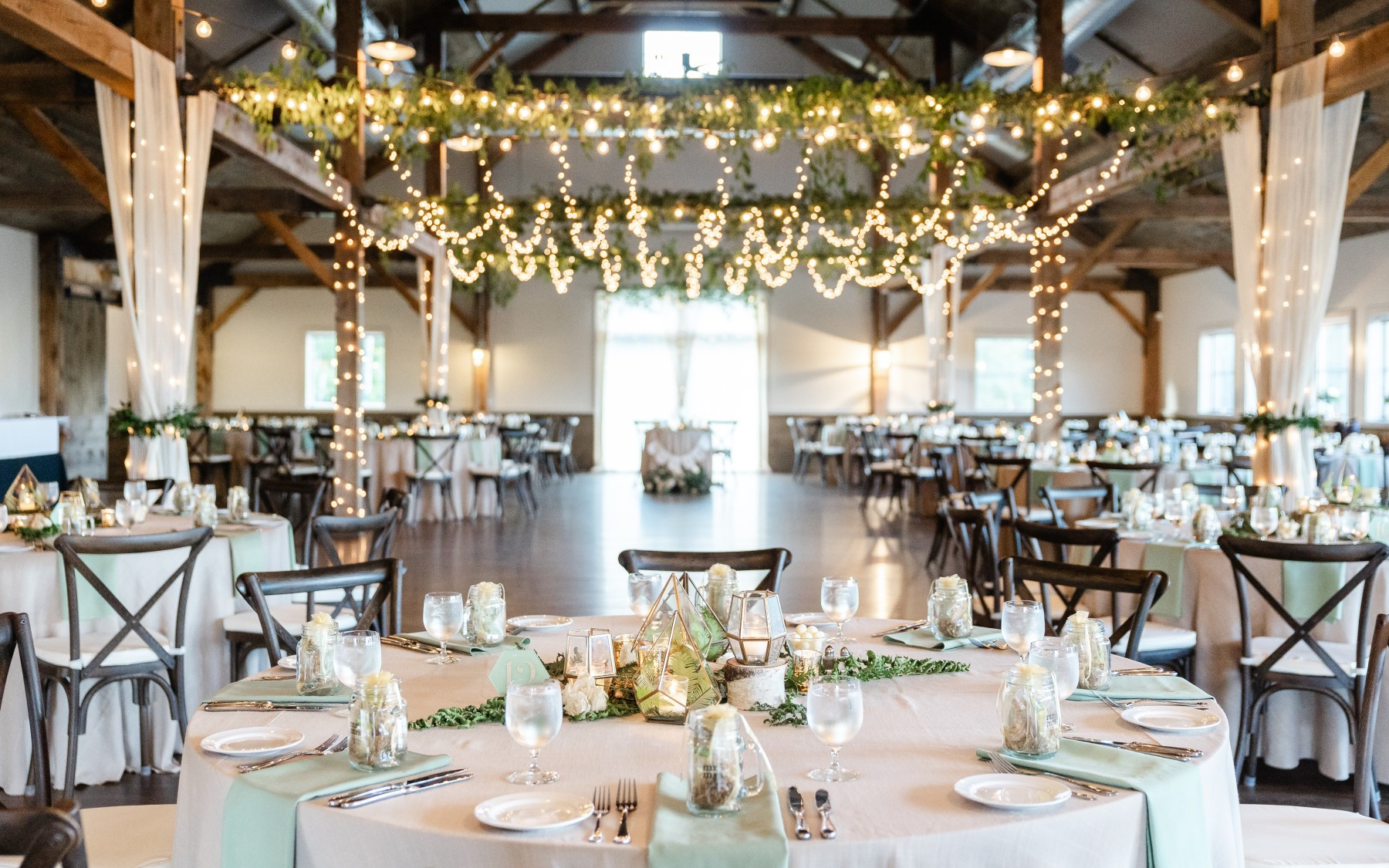 event barn wide angle featuring table rounds with green linens