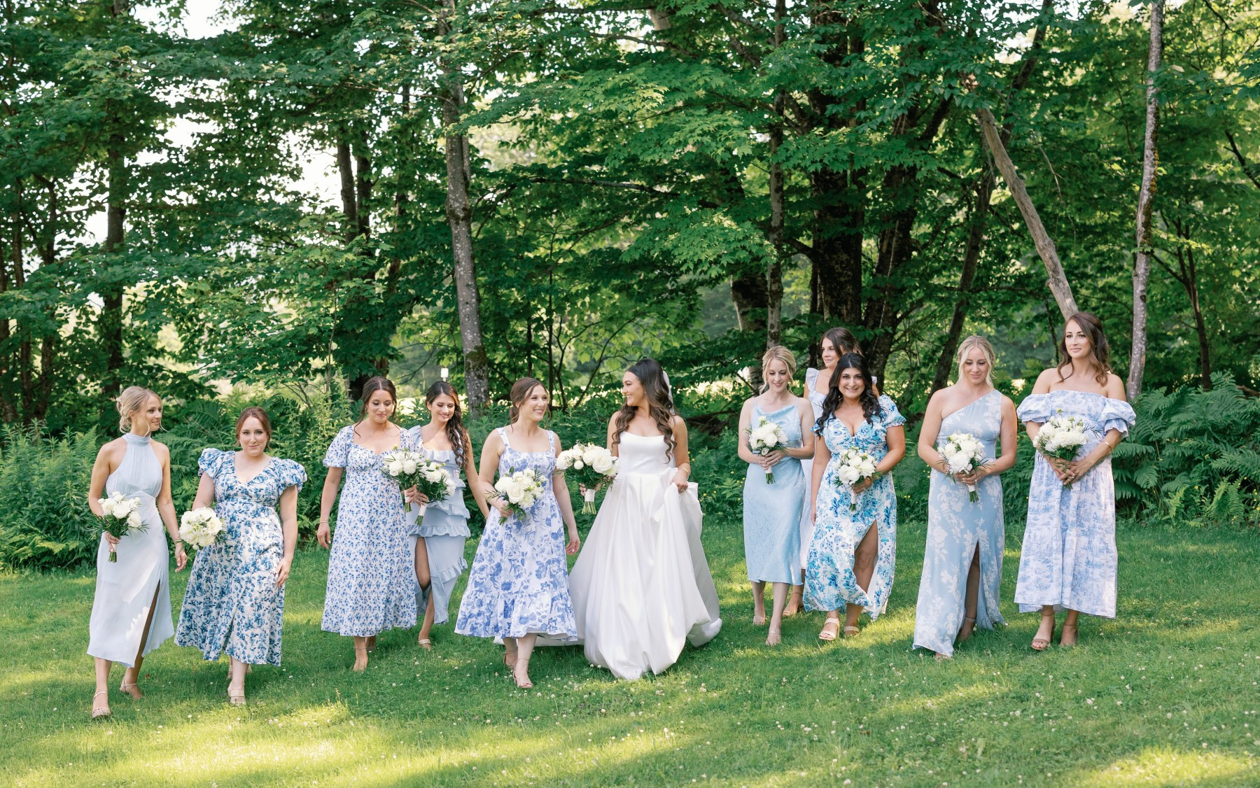 bride walking with bridesmaids in blue dresses towards camera.