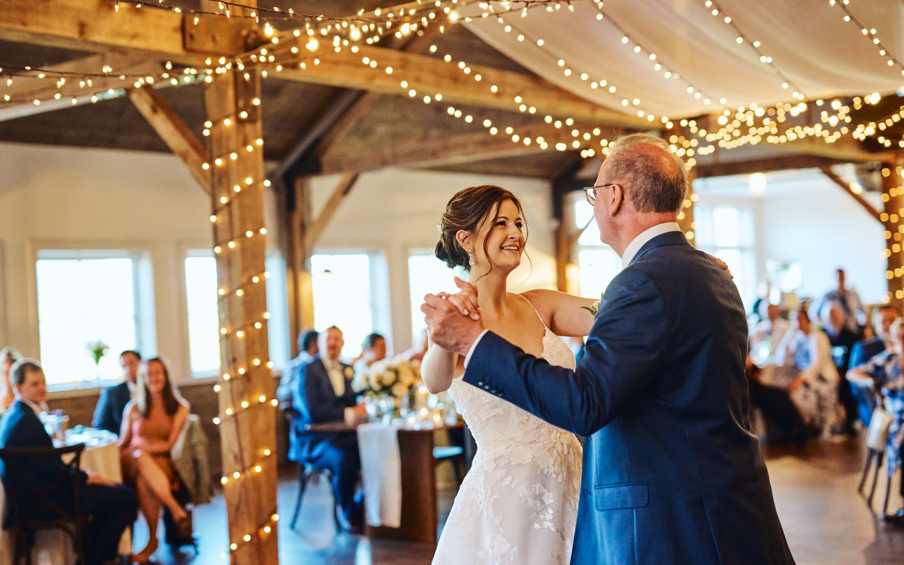 bride and father of bride dancing under event barn and lighting.