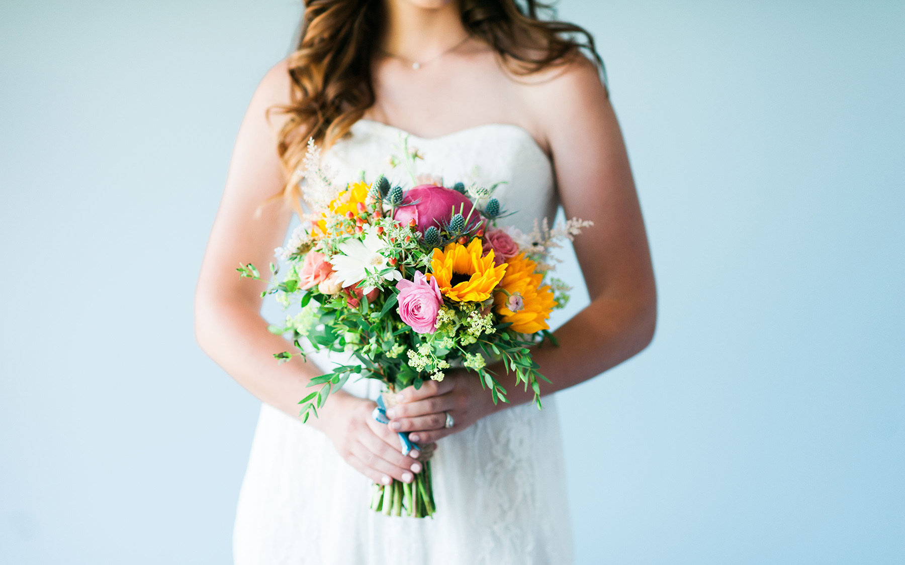 Woman in white bridal dress holding bouquet of brightly colored flowers of various colors at Mountain Top Inn & Resort in Chittenden, VT