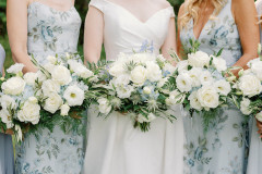 bride in white, bridesmaids in blue floral dresses...holding white bouquets.
