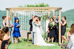 Bride and groom standing under chuppah during outdoor summer wedding cermony.