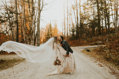 bride and groom kissing on a road with veil flowing.
