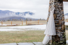 wedding dress photo hanging from stone pillar with foggy mountains in the background.