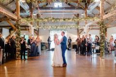 Bride and groom having their first dance in wedding barn. All the family and friends surrounding the dance floor to watch in excitement.