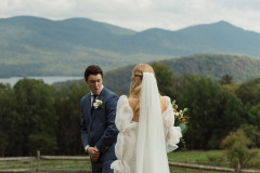 first look photo of groom looking at bride after he turns around. green mountains and lake in the background